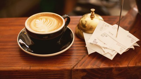 Geld ausgeben für Kaffee: Tasse Kaffee neben Quittungen