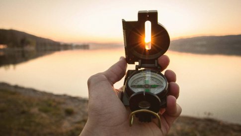 Jemand hält einen Kompass in Richtung Sonne. Das steht symbolisch für Purpose, den Sinn und die Richtung des eigenen Lebens.